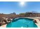 Backyard pool with rock details, surrounded by desert landscaping and block fencing for added privacy at 22727 W Papago St, Buckeye, AZ 85326