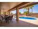 A covered backyard patio with dining table and a beautiful view of the pool and landscaping at 24832 S Boxwood Dr, Sun Lakes, AZ 85248