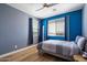Cozy bedroom with blue walls, a comfortable bed, and a window with curtains that provides natural light at 2517 W Balao Dr, Phoenix, AZ 85085