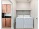 Convenient laundry room with modern washer and dryer, shelving, next to cabinets with stone countertop at 4695 N 204Th Ave, Buckeye, AZ 85396