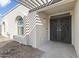 Inviting entryway with arched windows, pergola, and custom front door with palm tree design at 5202 E Marconi Ave, Scottsdale, AZ 85254