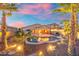 A stunning backyard showcasing a pool, palm trees, desert landscaping, and a covered patio lit with string lights at sunset at 835 E Virgo Pl, Chandler, AZ 85249