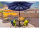Outdoor seating area with an umbrella, table, and chairs with throw pillows on a concrete patio with desert landscaping at 835 E Virgo Pl, Chandler, AZ 85249