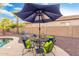 Outdoor seating area with an umbrella, table, and chairs with throw pillows on a concrete patio at 835 E Virgo Pl, Chandler, AZ 85249