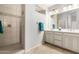 Bright bathroom features a double sink vanity, tiled floors, and a glass-enclosed shower with tile surround at 9144 W Surrey Dr, Peoria, AZ 85381