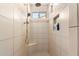 Tiled shower with a rain shower head, handheld shower, bench, niche, and window at 9144 W Surrey Dr, Peoria, AZ 85381