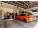 A well-lit garage with an orange car parked inside and storage shelves along the back wall at 9716 N 3Rd Dr, Phoenix, AZ 85021