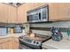 Well-lit kitchen featuring stainless steel microwave and stove, light colored countertop and dark stone backsplash at 9716 N 3Rd Dr, Phoenix, AZ 85021