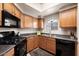 Classic kitchen with wood cabinets and modern black appliances set under a window at 10030 W Indian School Rd # 203, Phoenix, AZ 85037