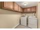 Bright laundry room includes a full-size washer, dryer, and upper cabinets for storage at 10713 N 36Th Ave, Phoenix, AZ 85029
