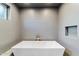 This bathroom features a modern white soaking tub, gray tiling, and a shower head at 1744 E Luke Ave, Phoenix, AZ 85016