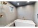 This bathroom features a modern white soaking tub, gray tiling, and a shower head at 1744 E Luke Ave, Phoenix, AZ 85016