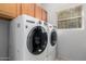 Bright laundry room with side by side washer and dryer and wood cabinets above at 18140 N Saddle Ridge Dr, Surprise, AZ 85374