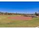 Well-maintained baseball field surrounded by lush green grass and mature trees, perfect for outdoor activities at 22644 W Mohave St, Buckeye, AZ 85326