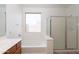A bathroom is shown with a tub with glass doors and a vanity with wood cabinets and a light at 32160 N Dog Leg Ct, San Tan Valley, AZ 85143