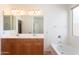 A bathroom is shown with double sinks, a large mirror with lights and a corner tub at 32160 N Dog Leg Ct, San Tan Valley, AZ 85143