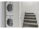 Hallway showcasing a laundry area with stacked washer and dryer, adjacent to carpeted stairs with white railing at 3845 E Greenway Rd # 230, Phoenix, AZ 85032