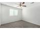 Bedroom with a ceiling fan, gray carpet, white walls, and a window at 5427 W Odeum Ln, Phoenix, AZ 85043