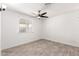 Neutral bedroom with gray floors, a window for natural light, and a ceiling fan at 6737 W Windsor Ave, Phoenix, AZ 85035