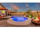 Inviting backyard pool with lounge chairs, vibrant landscaping, and ambient string lights at dusk at 715 E Blossom Rd, San Tan Valley, AZ 85143