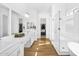 Bright main bathroom showcasing double sinks, wood floors, walk in shower, separate tub and a doorway to the walk-in closet at 8140 E June St, Mesa, AZ 85207