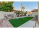 Cozy backyard featuring artificial grass, a patio, and mature palm trees for added privacy and shade at 826 W Royal Palms Dr, Gilbert, AZ 85233