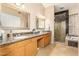 Spacious bathroom boasts dual sinks with granite countertops, wood cabinetry, and a separate glass-enclosed shower at 826 W Royal Palms Dr, Gilbert, AZ 85233