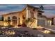 Stunning two-story home with a three-car garage, mature landscaping, and inviting exterior lighting at twilight at 826 W Royal Palms Dr, Gilbert, AZ 85233