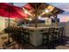 Outdoor kitchen has granite countertops, grill, and seating underneath a pergola with red umbrella at 826 W Royal Palms Dr, Gilbert, AZ 85233