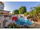 Backyard pool with rock waterfall, lush tropical landscaping, and a covered patio with outdoor dining area at 826 W Royal Palms Dr, Gilbert, AZ 85233