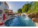 Backyard pool featuring a rock waterfall, a basketball hoop, and a covered patio with outdoor seating at 826 W Royal Palms Dr, Gilbert, AZ 85233