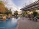 Beautiful backyard pool with a pergola-covered patio, lush landscaping, and serene water features at 8433 E Cholla St, Scottsdale, AZ 85260