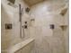 Travertine shower featuring bronze hardware, built-in shelves, and a pebble floor at 8433 E Cholla St, Scottsdale, AZ 85260