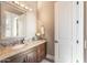 A well-lit bathroom with a granite countertop, decorative mirror and a white paneled door at 11225 E Starflower Ct, Chandler, AZ 85249