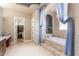 Gorgeous bathroom featuring a soaking tub with blue curtains, and a walk-in closet at 11225 E Starflower Ct, Chandler, AZ 85249