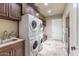 Functional laundry room with stacked washer and dryer, sink, and custom cabinets at 11225 E Starflower Ct, Chandler, AZ 85249
