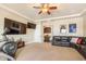 Spacious living room with ceiling fan, mounted televisions, and black leather couches at 11225 E Starflower Ct, Chandler, AZ 85249