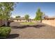 Sprawling backyard featuring a pool, artificial turf, mature trees, and ample space for outdoor enjoyment at 14302 W Laurel Ln, Surprise, AZ 85379