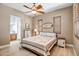 Comfortable bedroom featuring a ceiling fan, plantation shutters, and ensuite bathroom at 14302 W Laurel Ln, Surprise, AZ 85379
