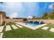 Backyard showcasing a sparkling pool with waterfall features and lush artificial turf and stone design at 15936 W Bonitos Dr, Goodyear, AZ 85395