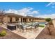 Wide backyard with a built-in outdoor grill and a pool featuring travertine decking and an inviting firepit area at 15936 W Bonitos Dr, Goodyear, AZ 85395