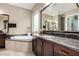 Bathroom featuring granite countertops, double sinks, soaking tub, and view to another bathroom at 15936 W Bonitos Dr, Goodyear, AZ 85395