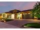 Twilight view of home with manicured front yard, brick driveway, and exterior lighting at 15936 W Bonitos Dr, Goodyear, AZ 85395