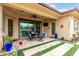 Inviting covered patio with a ceiling fan, outdoor seating, television and landscaped stone and artificial turf flooring at 15936 W Bonitos Dr, Goodyear, AZ 85395