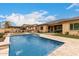 Backyard pool featuring travertine decking, stone waterfall features, pergola covered outdoor kitchen and a backyard firepit at 15936 W Bonitos Dr, Goodyear, AZ 85395
