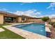 Backyard pool with a serene waterfall feature and a well-designed outdoor living space beyond the pool at 15936 W Bonitos Dr, Goodyear, AZ 85395