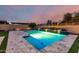 Swimming pool with tiled accents and water features, complemented by lush landscaping and lighting at 15936 W Bonitos Dr, Goodyear, AZ 85395