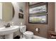 Stylish half-bathroom boasts a round mirror, pedestal sink, toilet and framed car pictures at 15936 W Bonitos Dr, Goodyear, AZ 85395