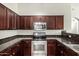 This kitchen features stainless steel appliances, dark wood cabinets, and granite countertops at 17150 N 23Rd St # 249, Phoenix, AZ 85022