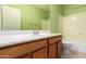 Bathroom featuring a light wood vanity, bright green walls, a shower-tub combo, and a white door at 2551 E Buena Vista Pl, Chandler, AZ 85249